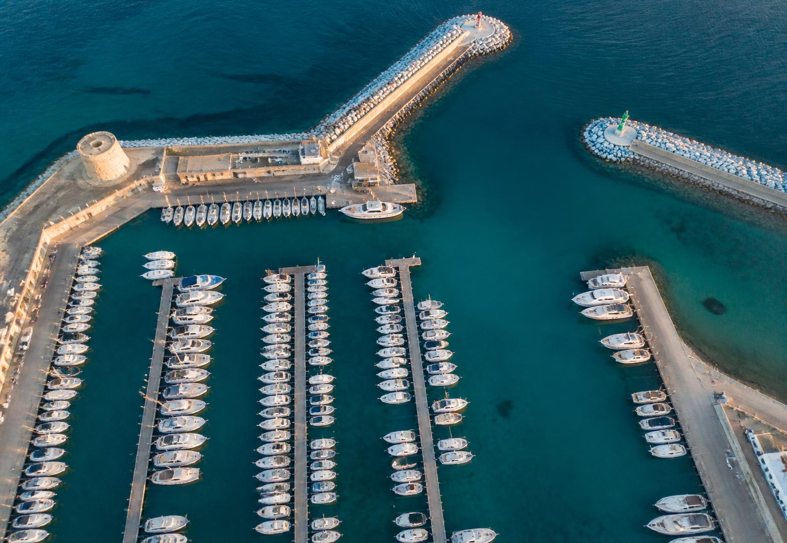 Vista aérea de un puerto deportivo mediterráneo con pantalanes y embarcaciones amarradas